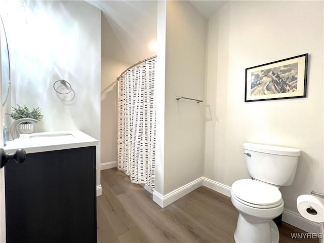 full bath with toilet, wood finished floors, vanity, curtained shower, and baseboards