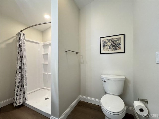 bathroom featuring baseboards, toilet, a stall shower, and wood finished floors
