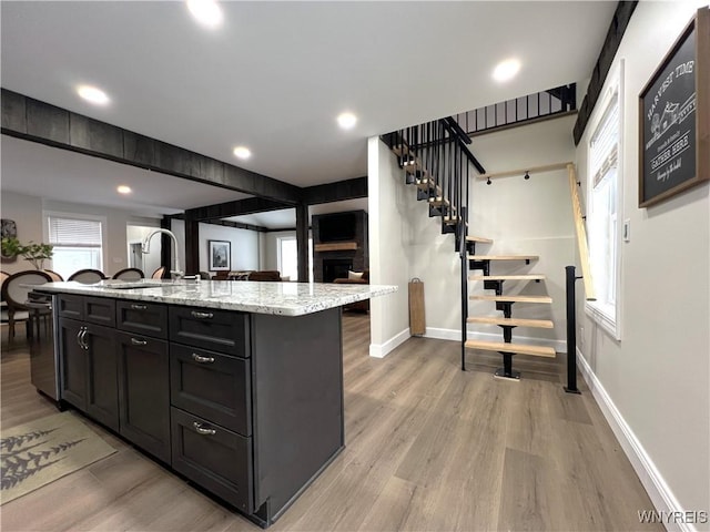 kitchen with light stone countertops, light wood-style flooring, and baseboards