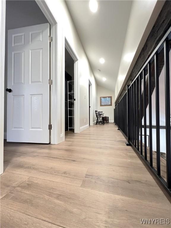corridor with recessed lighting, light wood-style flooring, lofted ceiling, and baseboards