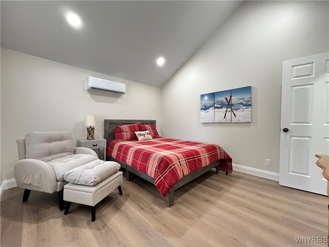 bedroom featuring a wall mounted air conditioner, baseboards, light wood-style floors, and high vaulted ceiling