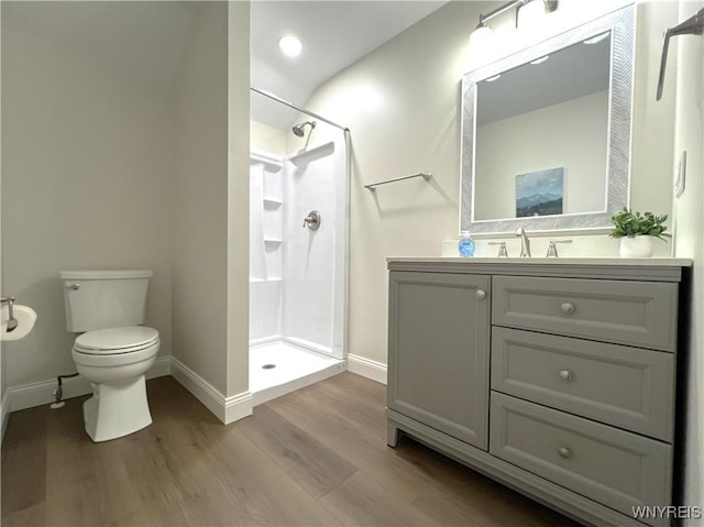 bathroom featuring baseboards, wood finished floors, and a walk in shower