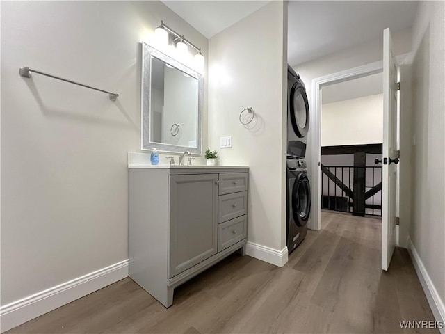 bathroom with vanity, baseboards, stacked washer / drying machine, and wood finished floors