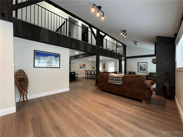 living area with baseboards, a towering ceiling, and wood finished floors