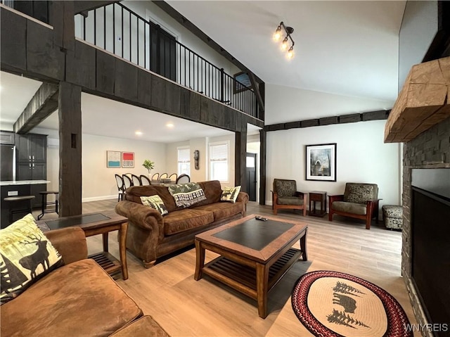 living area with a fireplace, light wood finished floors, and a towering ceiling