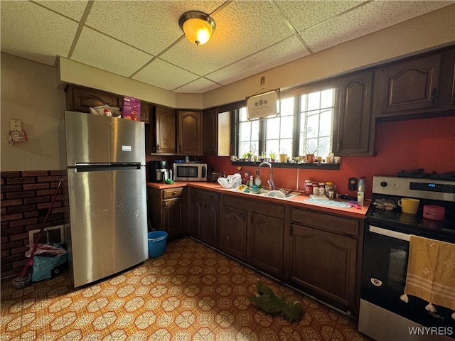 kitchen featuring light countertops, a paneled ceiling, appliances with stainless steel finishes, and a sink