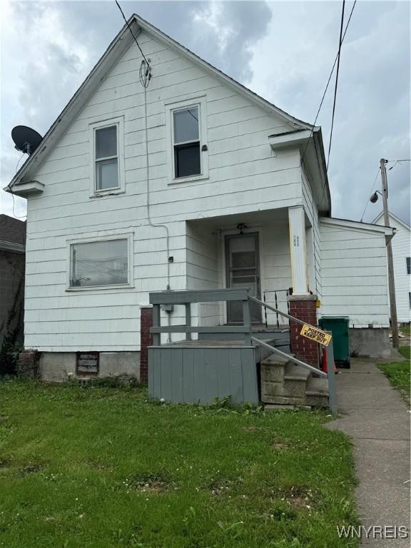 rear view of house featuring a lawn and covered porch