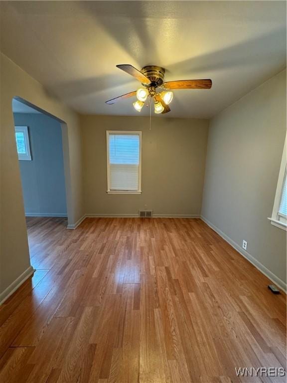 empty room with ceiling fan, baseboards, wood finished floors, and visible vents