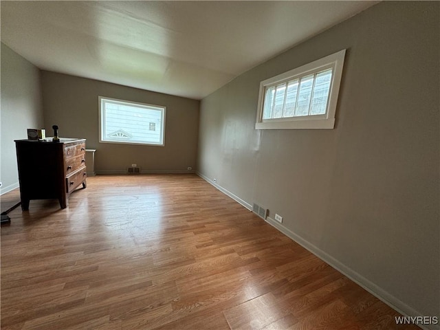 bonus room featuring baseboards, a healthy amount of sunlight, wood finished floors, and visible vents