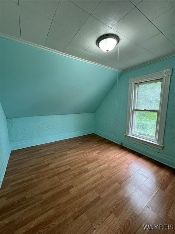 bonus room with baseboards, vaulted ceiling, and wood finished floors