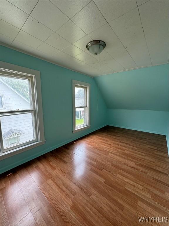 bonus room with vaulted ceiling, wood finished floors, and baseboards