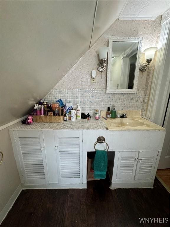 bathroom featuring lofted ceiling, wood finished floors, and tasteful backsplash