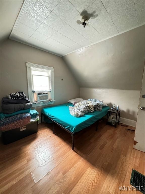 bedroom featuring vaulted ceiling, wood finished floors, and cooling unit
