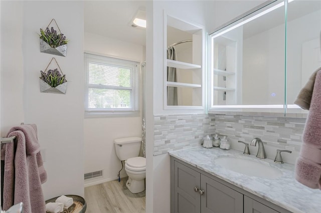 full bathroom with wood finished floors, decorative backsplash, vanity, toilet, and visible vents
