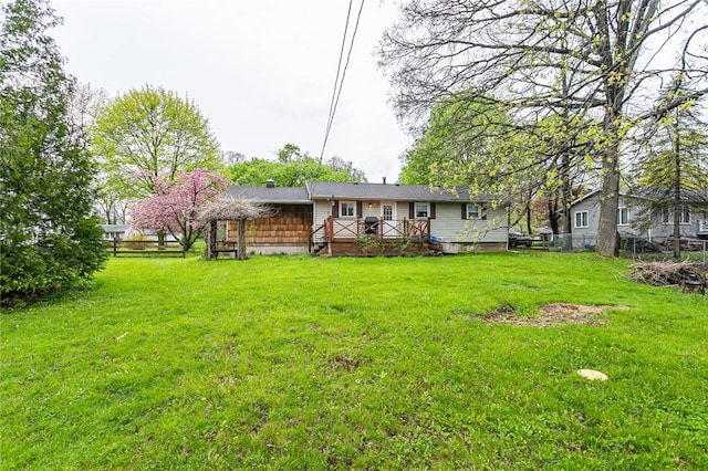 rear view of house with a lawn, a wooden deck, and fence