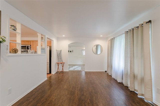 interior space with arched walkways, dark wood finished floors, baseboards, and recessed lighting