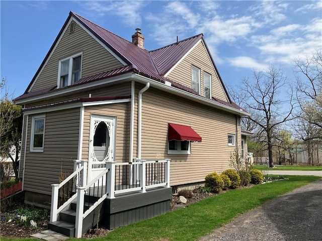 exterior space featuring a chimney and metal roof