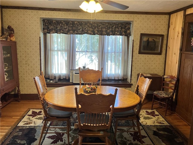 dining room with wallpapered walls, wood finished floors, a ceiling fan, and baseboards