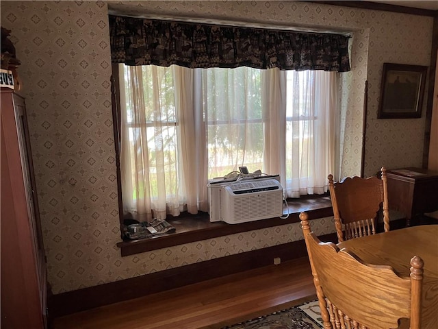 dining space featuring a wealth of natural light, wood finished floors, wallpapered walls, and baseboards
