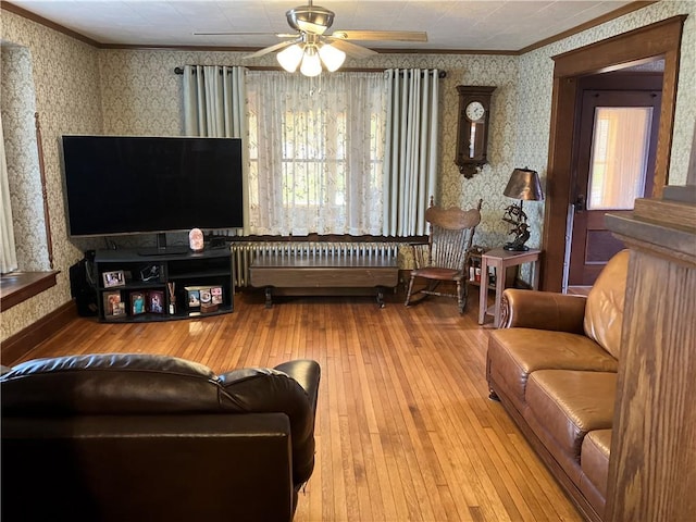 living room featuring wallpapered walls, hardwood / wood-style flooring, ceiling fan, radiator, and ornamental molding