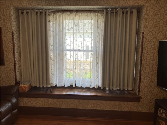 interior space with wallpapered walls, wood finished floors, and a healthy amount of sunlight