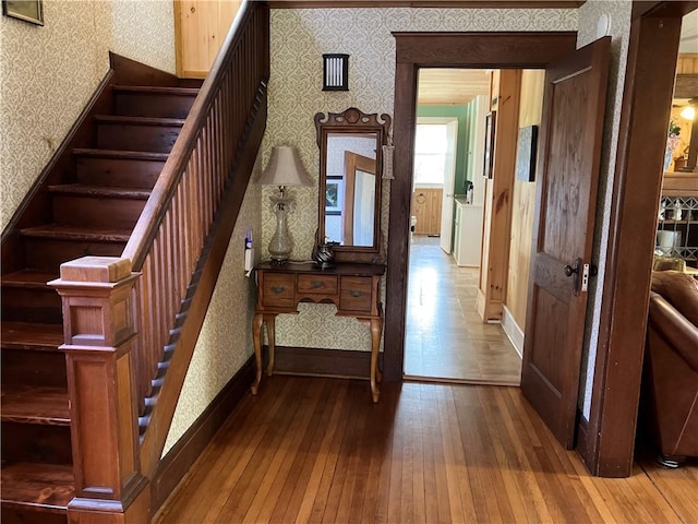 stairway with baseboards, hardwood / wood-style floors, and wallpapered walls
