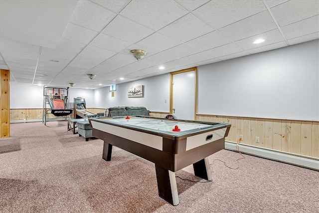 game room featuring a baseboard radiator, a wainscoted wall, carpet, wood walls, and a paneled ceiling