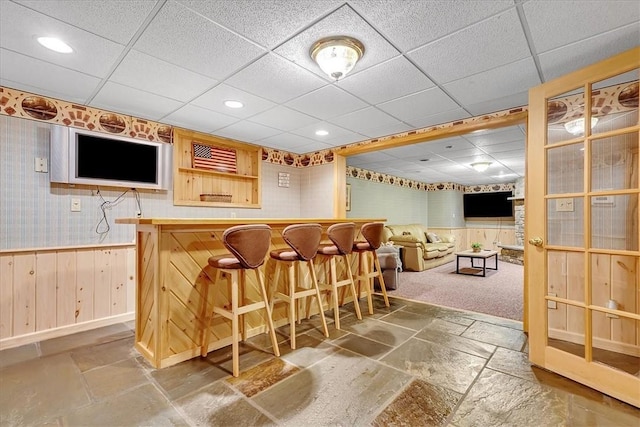 bar with recessed lighting, stone tile flooring, a paneled ceiling, and a bar