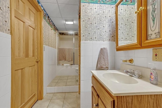full bath with toilet, tile walls, an enclosed shower, wallpapered walls, and vanity