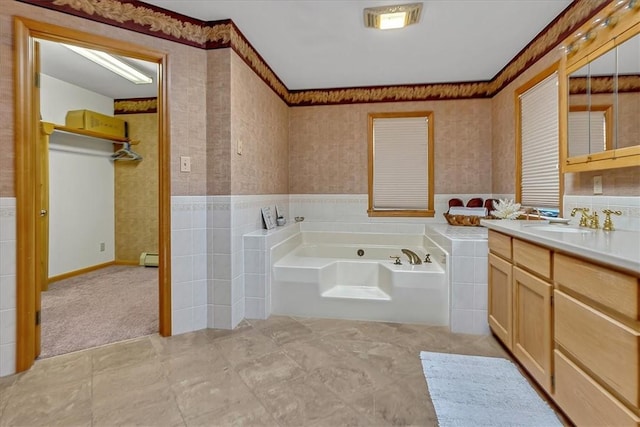 bathroom featuring a baseboard heating unit, a garden tub, vanity, and wainscoting
