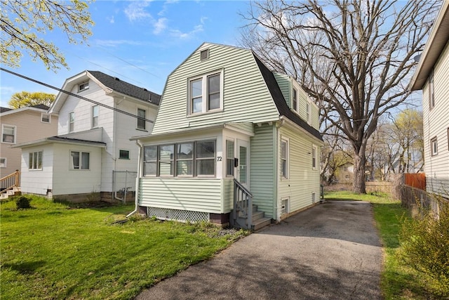 exterior space featuring fence, entry steps, a gambrel roof, a yard, and aphalt driveway