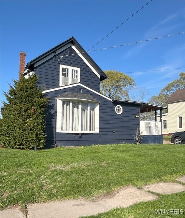 view of side of home featuring a chimney and a yard