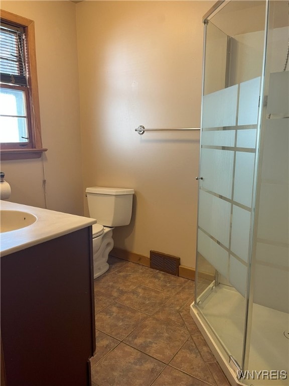 bathroom with toilet, baseboards, visible vents, a shower stall, and vanity