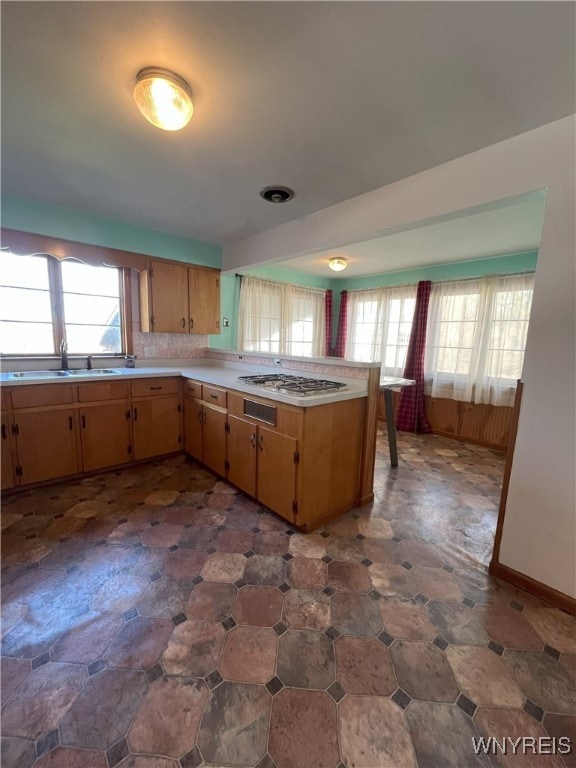 kitchen with light countertops, gas stovetop, a healthy amount of sunlight, and a sink