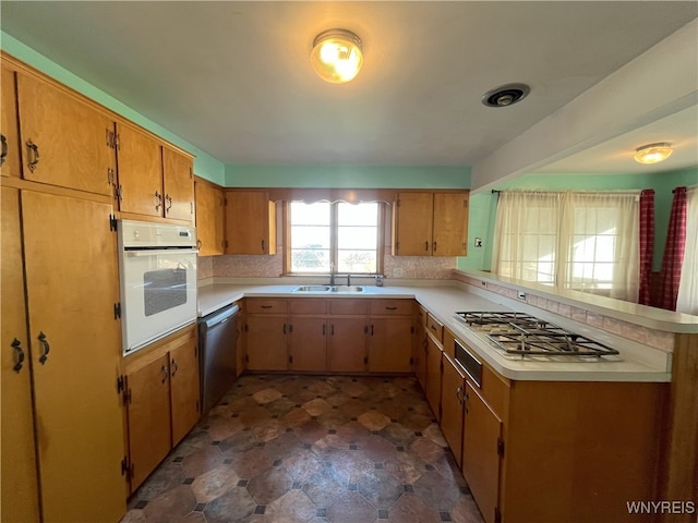 kitchen featuring light countertops, appliances with stainless steel finishes, decorative backsplash, and a sink