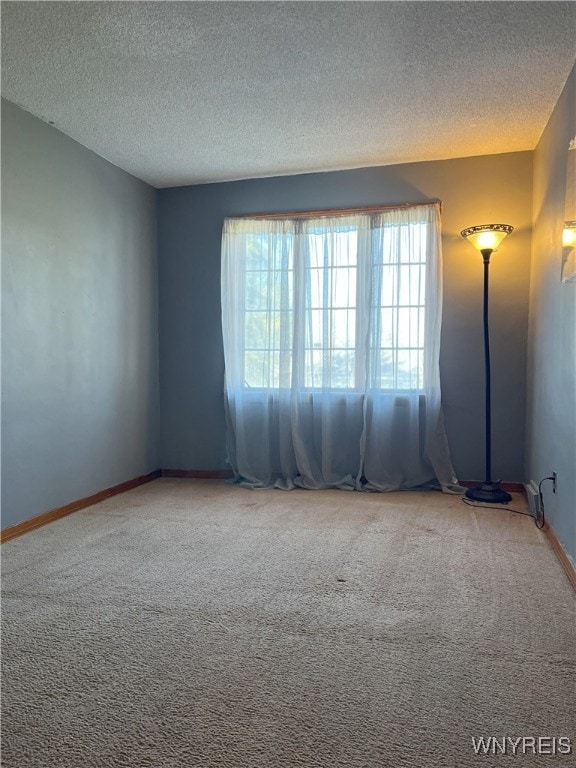 carpeted empty room featuring baseboards and a textured ceiling