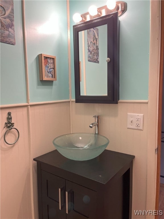 bathroom with a wainscoted wall, vanity, and a decorative wall