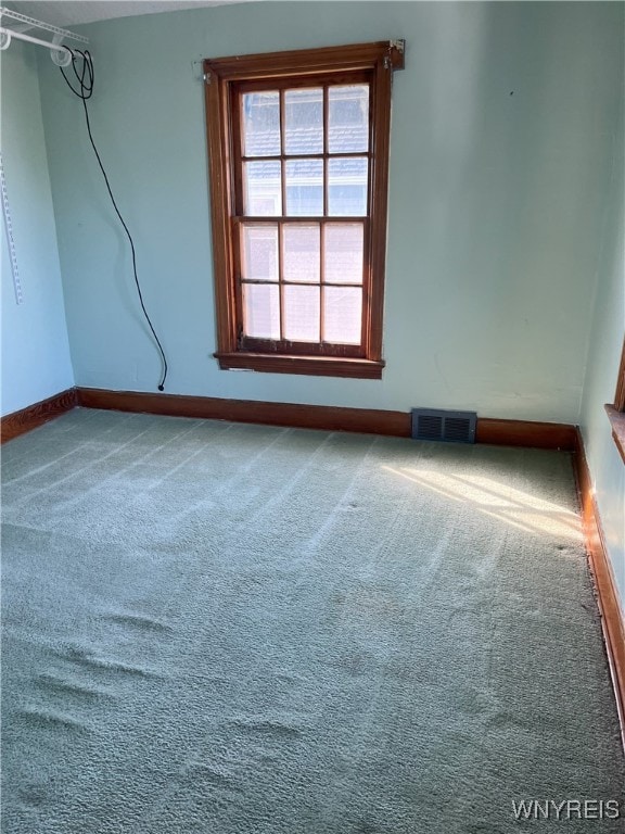carpeted spare room featuring visible vents and baseboards