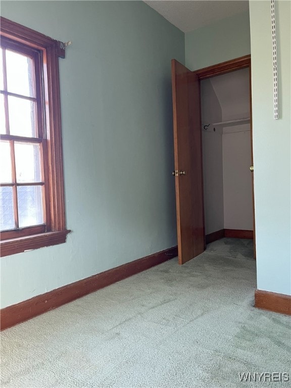 unfurnished bedroom featuring baseboards, carpet flooring, a closet, and multiple windows