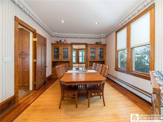 dining room with wallpapered walls, baseboard heating, light wood-style floors, and ornamental molding