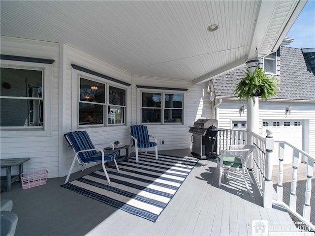 wooden deck with an attached garage and a grill