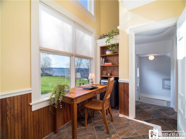 office area with stone tile floors, a wainscoted wall, and wooden walls