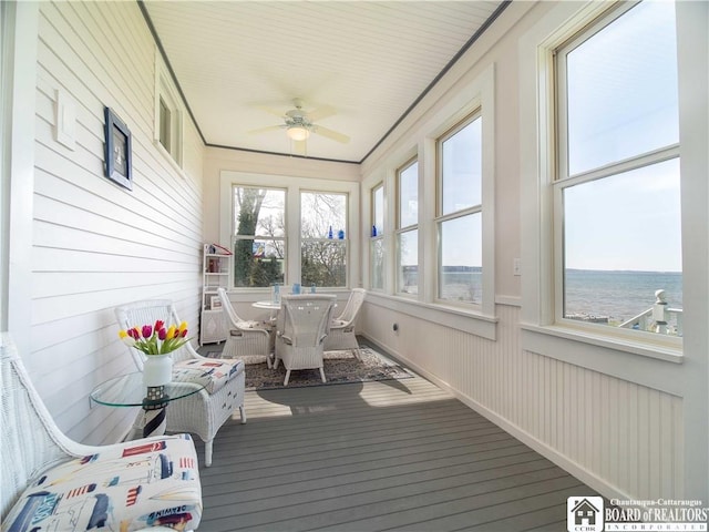 sunroom / solarium with outdoor dining area, a wooden deck, wood walls, and ceiling fan