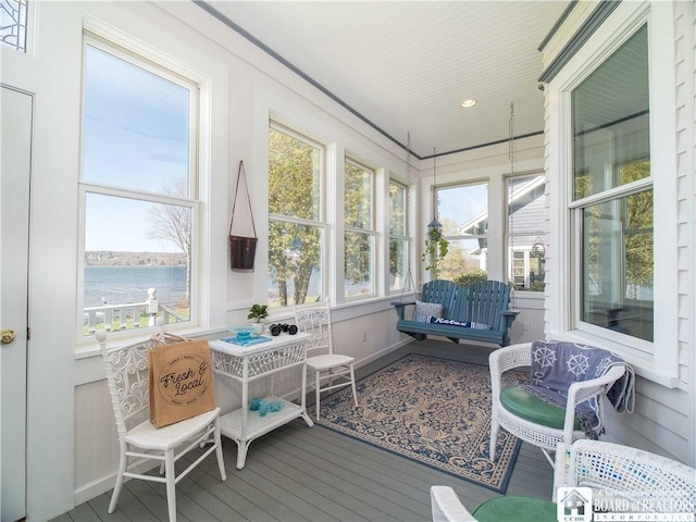 sunroom featuring a water view
