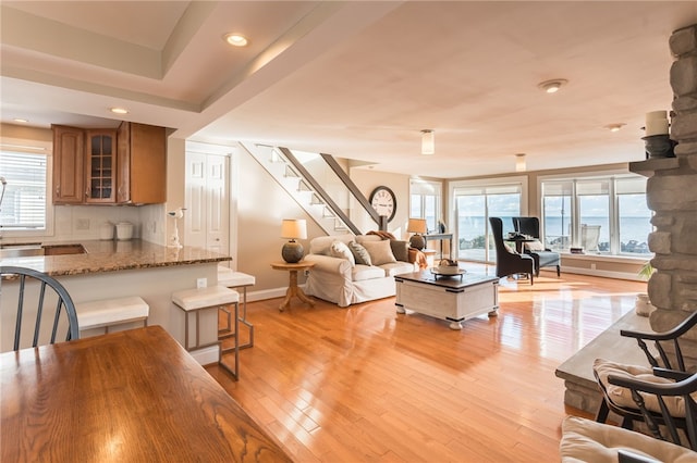 living room with recessed lighting, stairway, baseboards, and light wood-type flooring