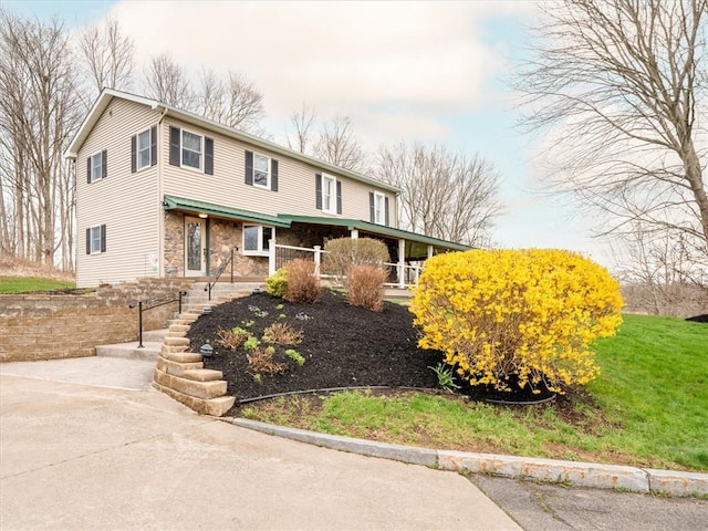 view of front of home featuring stone siding, a front yard, and covered porch