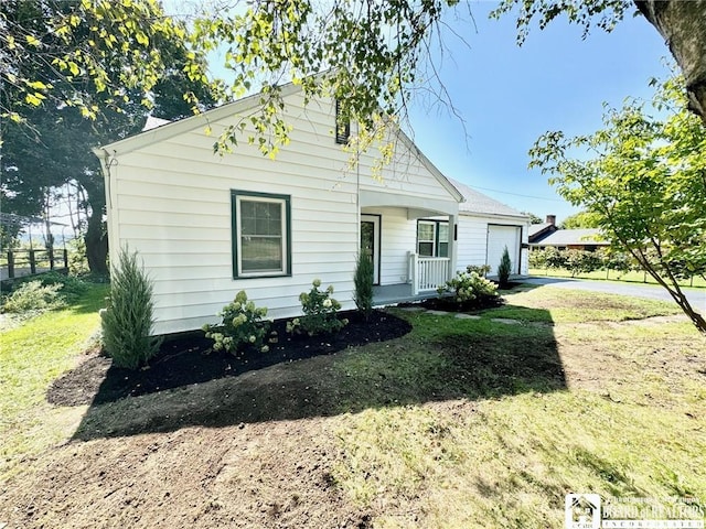 bungalow-style house with a front lawn, driveway, a porch, fence, and an attached garage