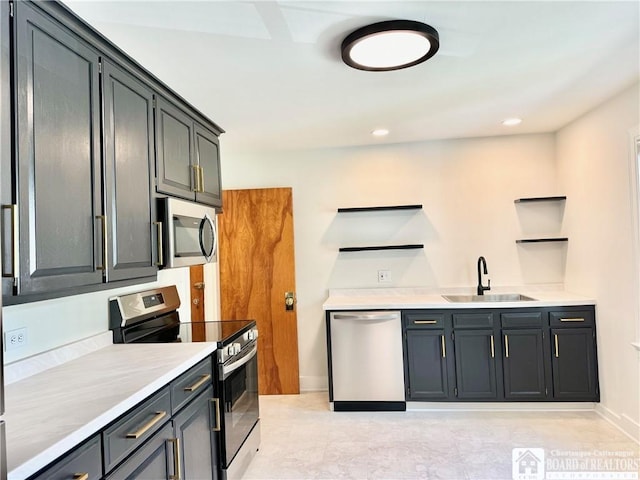 kitchen featuring open shelves, a sink, light countertops, baseboards, and appliances with stainless steel finishes