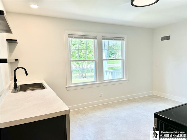 interior space with a sink, baseboards, visible vents, black electric range oven, and light floors