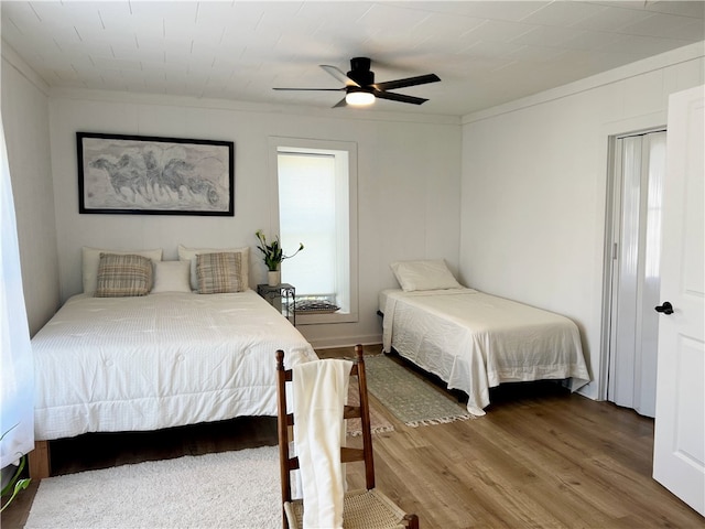 bedroom featuring ceiling fan, crown molding, and wood finished floors